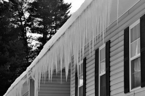 Long heavy icicles posing an ice damage risk to the burdened eaves of a building after a severe winter storm.